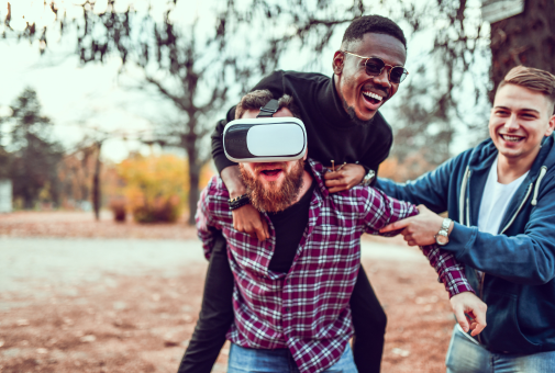 Three men fooling around with a virtual reality headset, having fun and goofing around